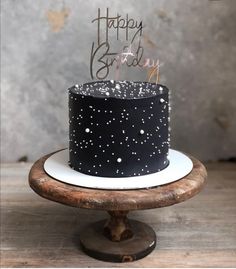 a black and white birthday cake sitting on top of a wooden table