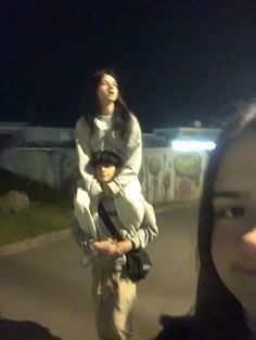 two people standing next to each other on a road at night with one person holding the camera