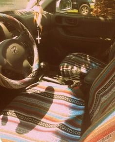 the interior of a car with a steering wheel and colorful blanket on the dash board