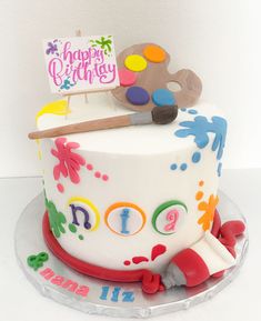 a birthday cake decorated with an artist's palette and paintbrush for a child's first birthday