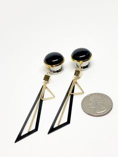 "Pair of plugs with gold and black geometric lightweight dangles. Sold in sets. Quantity of 1=1pair. Cap is 18mm for all sizes listed. Dangles about 3\" I tried to show it in the photos, but the gold shade for the setting of the black cap is more of a yellow gold and the dangle components are a softer shade. Gauge Sizes 1/2\" (12mm) 9/16\" (14mm) 5/8\" (16mm) Available plug base materials are the following: 1. Clear acrylic screw back tunnels 2. Crocodile wood single flared with o-ring 3. Surgic Nickel-free Black Metal Plug Earrings, Black Geometric Jewelry, Modern Black Drop Plug Earrings, Modern Adjustable Nickel-free Plug Earrings, Adjustable Geometric Black Jewelry, Adjustable Black Geometric Jewelry, Modern Adjustable Black Earrings, Gauge Sizes, Dangle Plugs