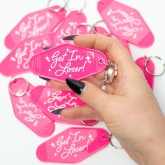 a hand holding a pink keychain with the words get in here written on it