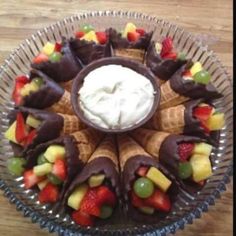 a plate with fruit and ice cream in it on top of a wooden table next to a glass bowl