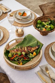 a table set with plates, bowls and utensils for an outdoor dinner party