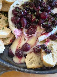 an assortment of cheeses and fruit are on a plate with bread slices in the background