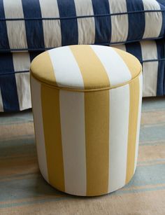 a yellow and white striped ottoman sitting on top of a rug