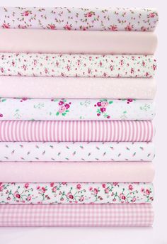 a stack of pink and white fabrics with flowers on them, all in different colors