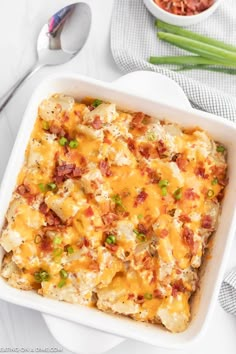 a casserole dish with potatoes, bacon and green onions in it on a white plate