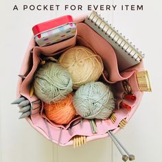 a pink purse filled with balls of yarn and knitting needles