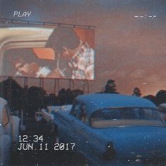 an old car is parked in front of a movie screen