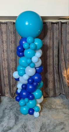 a blue and white balloon column in front of curtains