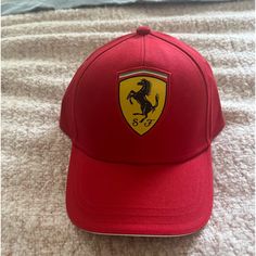 a red cap with the ferrari logo on it is laying on a white bed sheet