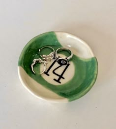 a green and white bowl with a pair of scissors in the shape of a horse