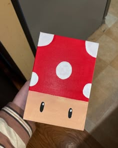 a person holding up a piece of paper with a mushroom on it's face