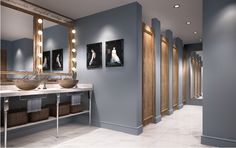 a bathroom with two sinks, mirrors and lights on the wall above them are pictures of women in white dresses