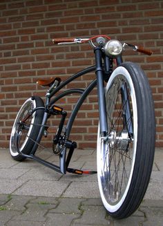 a black and white bicycle parked next to a brick wall