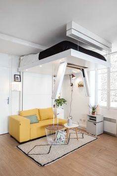 a living room with a yellow couch and a loft bed in the middle of it