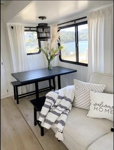 a living room with a couch, table and window looking out onto the water in front of it