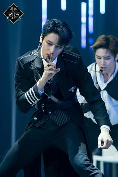 two men in black and white outfits performing on stage