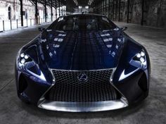 the front end of a blue sports car parked in a parking garage with its lights on