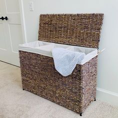 a wicker storage basket with a blanket on top in the corner of a room