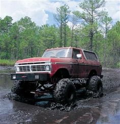 a red truck is driving through some mud