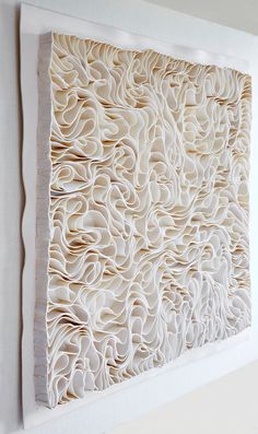 an art piece made out of white paper with wavy lines on the bottom and sides