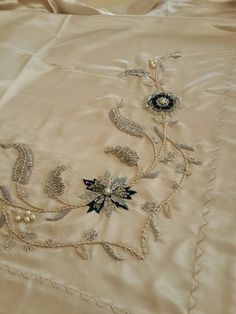 a close up of an embroidered cloth with beads and flowers on it, laying on a bed