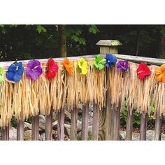 several colorful flowers are tied to the side of a fence with straws on it