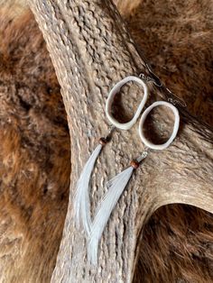 two pairs of scissors are hanging from a tree branch with long white tassels