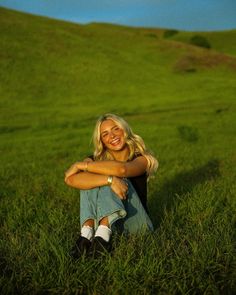 a woman sitting in the grass with her arms crossed