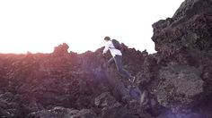 a man climbing up the side of a rocky mountain with his backpack on and one foot in the air