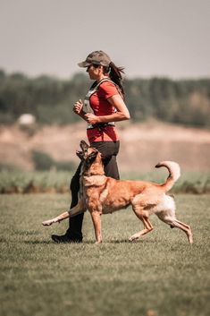 a woman is running with her dog in the field