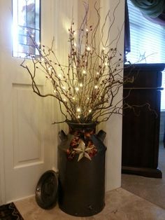 a vase with branches and lights in it on the floor next to a door way