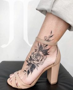 a woman's foot with a rose tattoo on the side of her leg and ankle