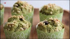 four cupcakes with green frosting and nuts in them