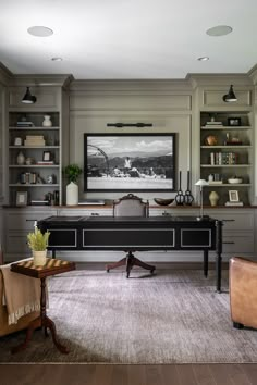 a room with two chairs, a desk and a bookcase in it that has pictures on the wall