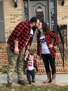 a man and woman kissing while standing in front of a house with a small child