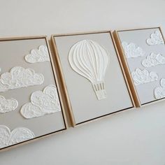 three framed pictures with white paper cutouts on them, each depicting a hot air balloon in the sky