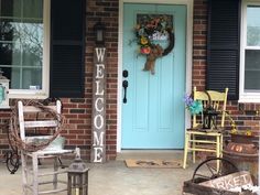 a welcome sign on the front door of a brick house with rocking chairs and a wreath