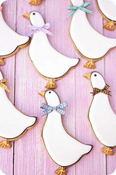 decorated cookies in the shape of ducks with bows on them sitting on a wooden table