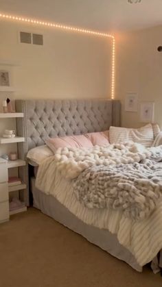 a bedroom with a large bed covered in blankets and pillows, lights on the wall