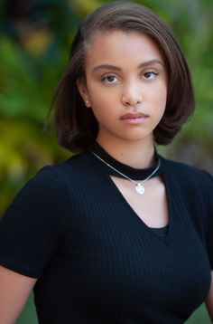 a young woman wearing a black shirt and necklace