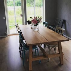 a wooden table with chairs around it in front of large windows and sliding glass doors