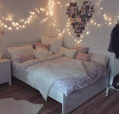 a white bed sitting in a bedroom next to a wall covered in pictures and lights