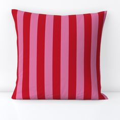 a pink and red striped pillow sitting on top of a white table