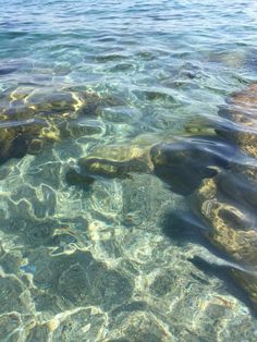 the water is crystal clear and there are some rocks in the middle of the ocean