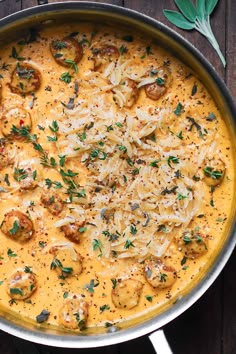 a pan filled with pasta and cheese on top of a wooden table next to green leaves