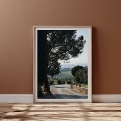 a framed photograph sitting on top of a wooden table next to a wall with a tree