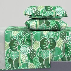 three green and white sheets stacked on top of each other in front of a gray wall